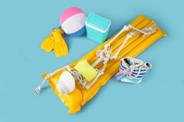 Mavi arka planda plaj aksesuarları olan insan iskeleti, üst manzara. Yaz tatili kavramı