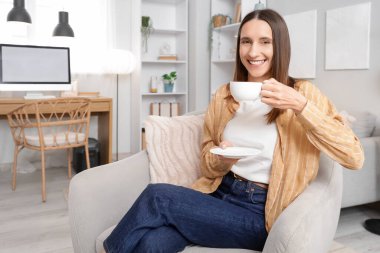 Evdeki gri koltukta çay içen güzel kadın.
