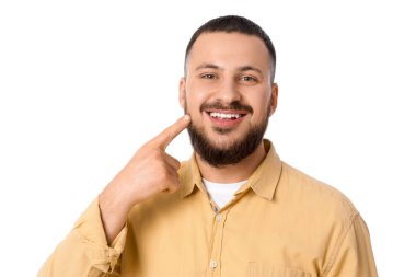 Genç adam beyaz arka plandaki gülüşüne işaret ediyor, yakın plan.