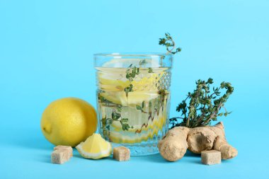 Bir bardak taze limon, üzerine zencefil ve kekik serpiştirilmiş su.