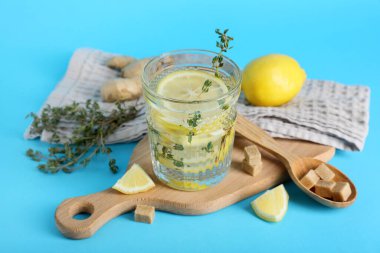 Bir bardak taze limon, üzerine zencefil ve kekik serpiştirilmiş su.