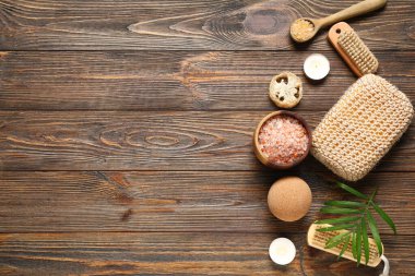 Kahverengi ahşap arka planda bir kase deniz tuzu ve banyo malzemesi ile güzel bir spa kompozisyonu.