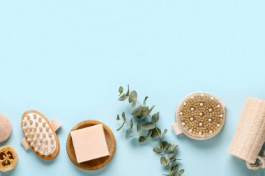 Masaj vücut fırçaları, sabun çubuğu ve mavi arka planda yeşil dal ile kompozisyon, yakın plan