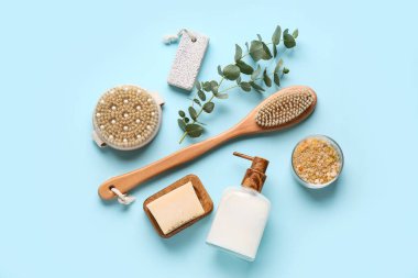 Masaj vücut fırçaları, sabun çubuğu ve mavi arka planda bir şişe kozmetik ürünle kompozisyon