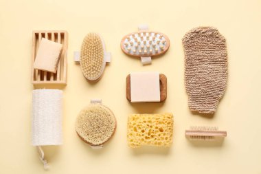 Bej arka planda masaj vücut fırçaları, sabun çubukları ve süngerlerle kompozisyon, yakın plan