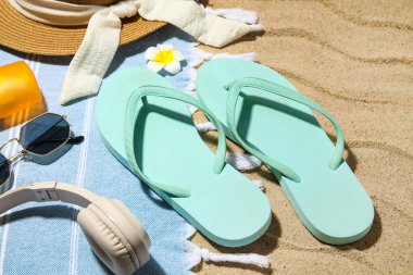 Plaj ayakkabıları, kulaklıkları ve kumsaldaki aksesuarları arka plan olarak, yakın plan.