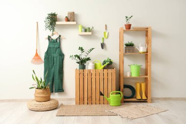 Bahçıvan üniforması, raf ünitesi ve bitkilerle dolu bir atölye.