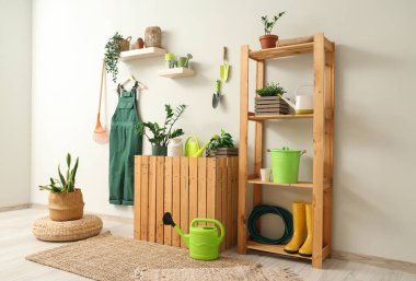 Bahçıvan üniforması, raf ünitesi ve bitkilerle dolu bir atölye.