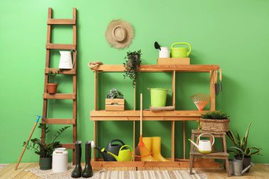 Bahçe aletleri, raf ünitesi ve merdiveni olan atölyenin içi