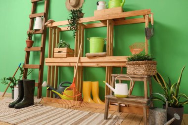 Bahçe aletleri, raf ünitesi ve merdiveni olan atölyenin içi