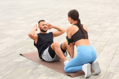 Kişisel antrenörü olan sporcu adam dışarıda mekik çekiyor.