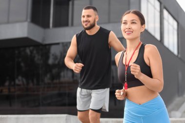 Kadın Asyalı özel antrenör ve erkek dışarıda koşuyor.