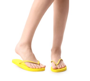 Beyaz arka planda sarı parmak arası terlik giyen kadın bacaklar.