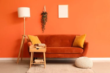 Kırmızı kanepesi, masası ve lambası olan şık bir oturma odası.