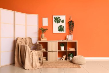 Hasır koltuğu, raf ünitesi ve katlanır ekranı olan şık bir oturma odası.