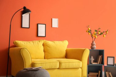 Sarı kanepesi, lambası ve kitaplığı olan şık bir oturma odası.