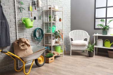 Raf üniteleri, bahçe aletleri ve koltuk ile atölyenin içi