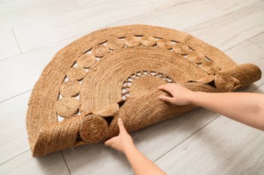 Kadın elleri yere hasır halı seriyor.