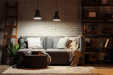 Geceleri kitap rafı, kanepe ve parlayan lambalar olan oturma odasının içinde.