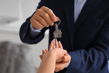 Erkek emlakçı mutfaktan kadına anahtar veriyor, yakın plan.