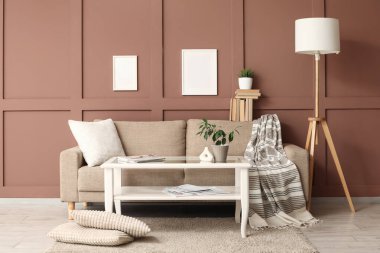 Oturma odasının içinde kanepe, cam masa ve boş çerçeveler var.