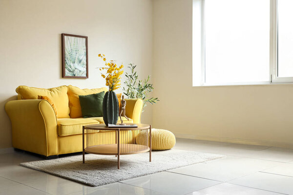 Interior of living room with sofa and artificial flowers on table