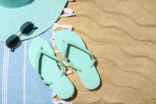 Arka plan olarak kumsalda plaj ayakkabıları ve plaj aksesuarları olan kompozisyon, yakın plan