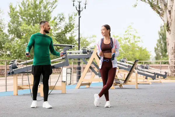 Genç Asyalı kadın ve spor sahasında ip atlayan kişisel antrenör.