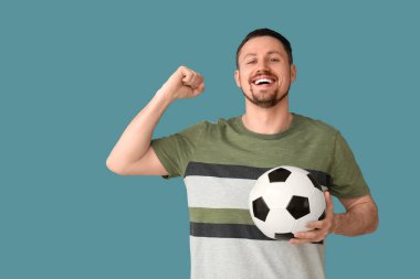 Mavi arka planda futbol topu olan mutlu adam.