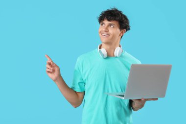 Dizüstü bilgisayarı mavi arka plandaki bir şeyi gösteren erkek programcı