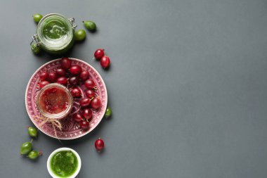 Gri arka planda lezzetli bektaşi üzümü reçeli olan kavanoz ve kase.