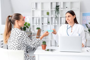 Kadın jinekolog klinikteki hastaya doğum kontrol hapı veriyor.