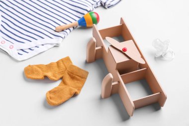 Gri arka planda bebek kıyafetleri, oyuncakları ve emziği olan kompozisyon