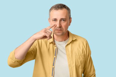 Olgun olmayan bir adam mavi arka planı işaret ediyor.