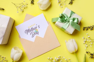 İçinde şenlikli kartpostal, çiçekler ve sarı arka planda hediye kutuları olan zarf. Anneler Günü kutlaması