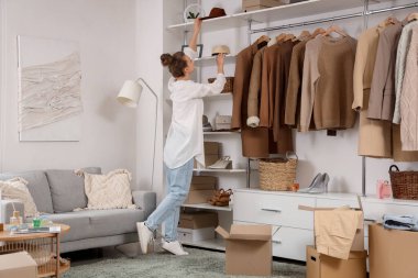 Soyunma odasında şık aksesuarlar düzenleyen elbise kutularıyla güzel genç bir kadın.