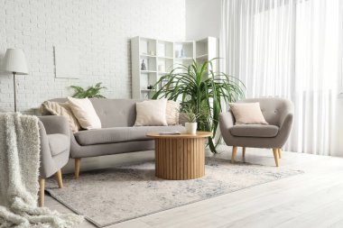 Oturma odasının içi kanepe, koltuk ve çiçeklerle dolu.