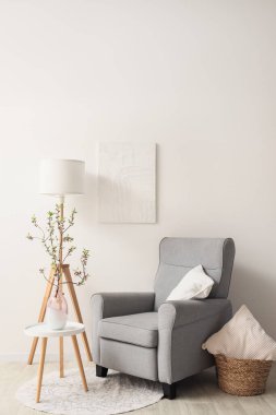 Oturma odasındaki beyaz duvarın yanında çiçek açan vazolardan oluşan gri koltuk ve kahve masası.