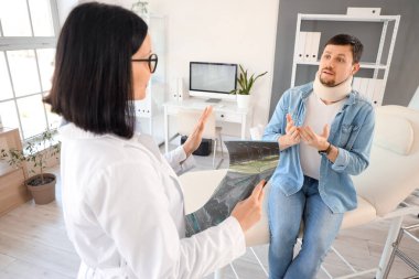 Yaralı genç bir adam, klinikte omurga röntgeniyle doktoru ziyaret ediyor.