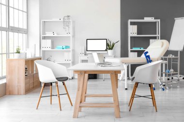 Masaları, kanepesi ve raf üniteleri olan bir tıp bürosu.