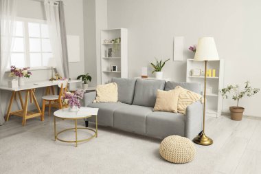 Kanepe, masa ve vazolarda leylak çiçekleriyle aydınlık oturma odasının içinde.