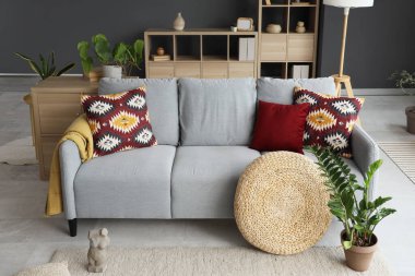 Şık yastıklı kanepe, puf ve bitki oturma odasında.