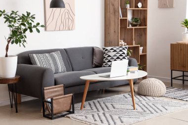 İçinde siyah kanepe, sehpa, çekmeceler ve raf ünitesi olan şık bir oturma odası.