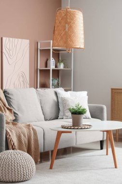 Gri kanepesi ve bej duvarın yanında kahve masası olan şık bir oturma odası.