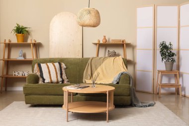 Katlanır perdeli, yeşil kanepeli, lambalı ve kahve masalı güzel bir oturma odası.