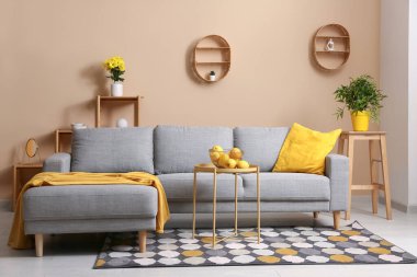 Gri kanepeli, sarı yastıklı ve portakallı modern oturma odasının içinde.