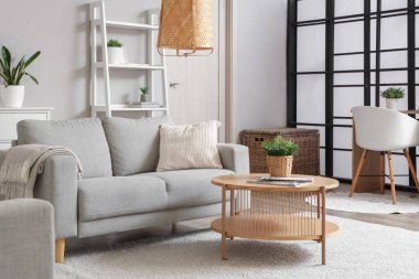 Gri kanepesi ve kahve masası olan aydınlık oturma odasının içinde.