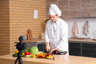 Taze sebzeli erkek şef mutfakta yemek pişirme videosu kaydediyor.