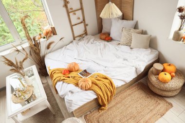 Şık bir yatak odası, rahat bir yatak, sehpa, kanepe ve balkabağı.