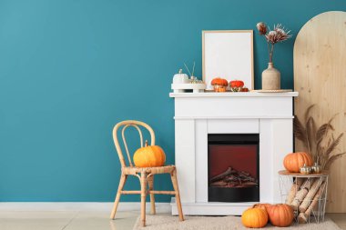 Beyaz şömine, sonbahar oturma odasında tahta kütükler ve balkabaklarıyla dolu sepet.